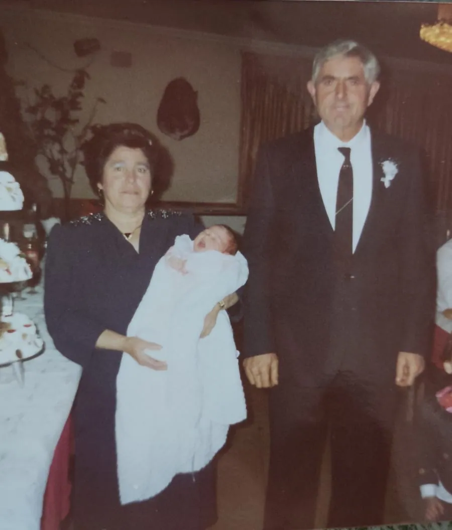 Los padres en el bautizo de su nieta, con un bebé en brazos