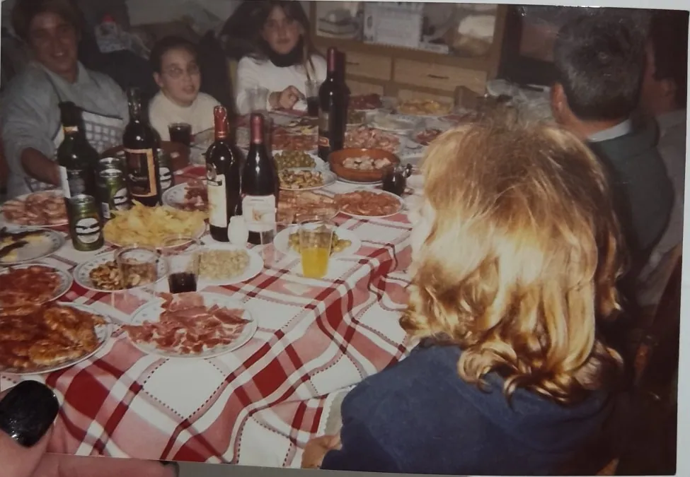 Mesa de familia llena de platos, con varias generaciones sentadas alrededor